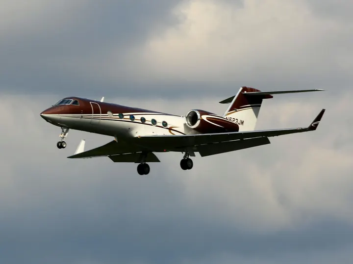 A light business jet in flight against a pale sky