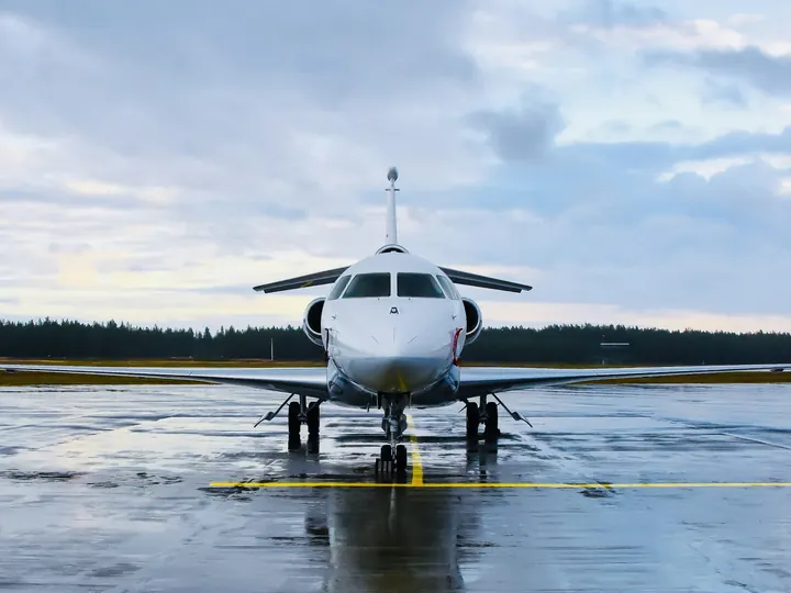 A business jet on a rain-wet ramp under a grey sky