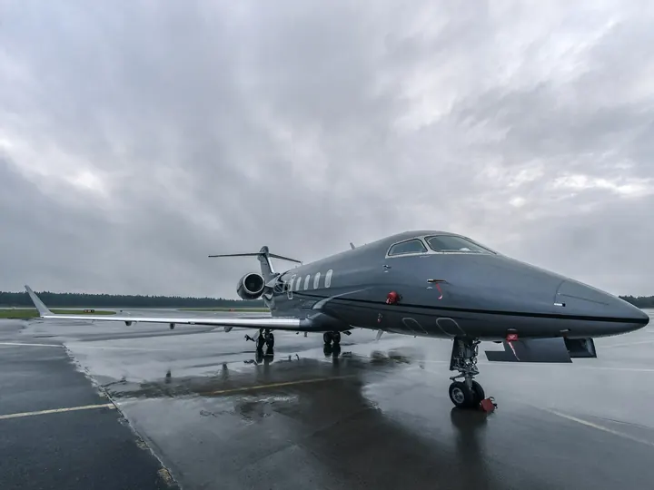 A business jet parked on a wet ramp at dusk