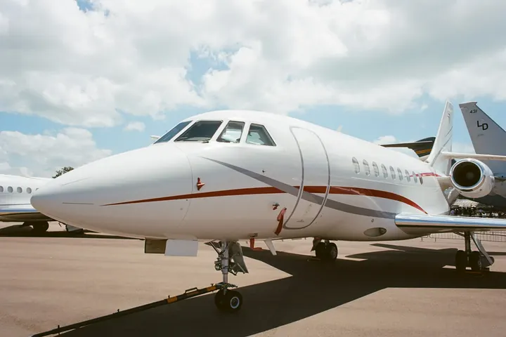 The nose and cockpit windows of a business jet parked on a ramp