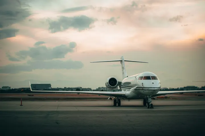 A business jet parked on an apron at dusk under a soft sky